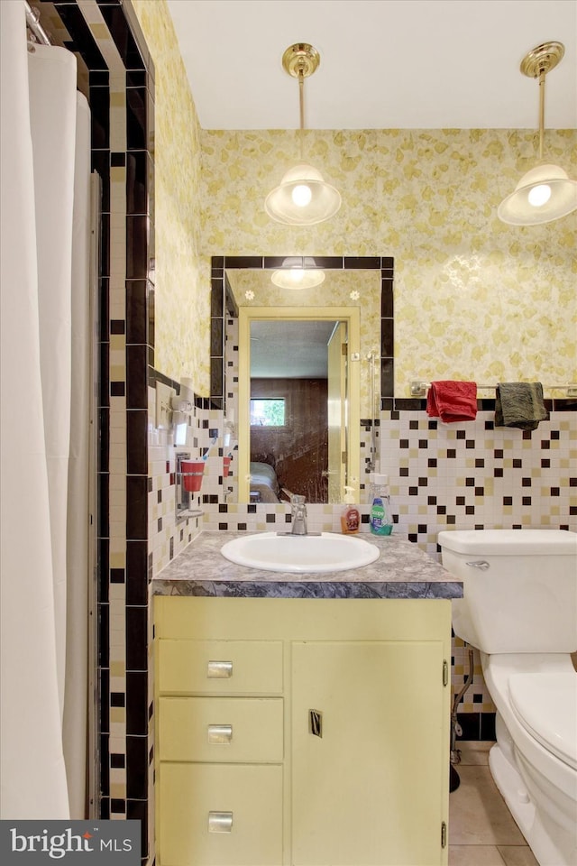 bathroom with vanity, toilet, tile walls, tile patterned flooring, and backsplash