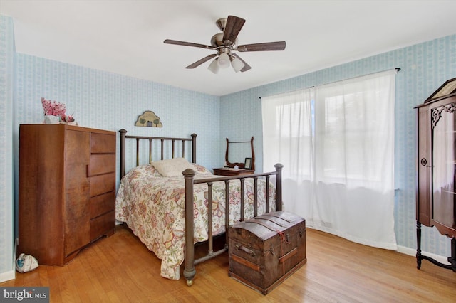 bedroom featuring wallpapered walls, wood finished floors, baseboards, and a ceiling fan