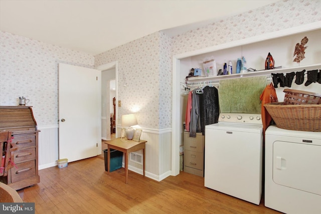 clothes washing area featuring a wainscoted wall, washer and clothes dryer, wallpapered walls, and light wood finished floors