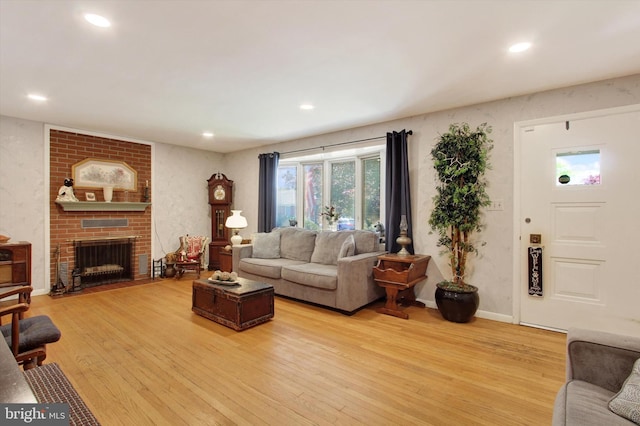 living room with light wood-style flooring, recessed lighting, a brick fireplace, and baseboards