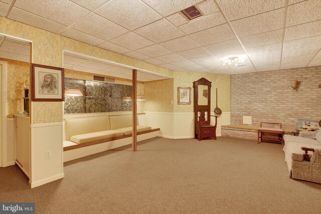 below grade area with wainscoting, a paneled ceiling, carpet floors, and wallpapered walls