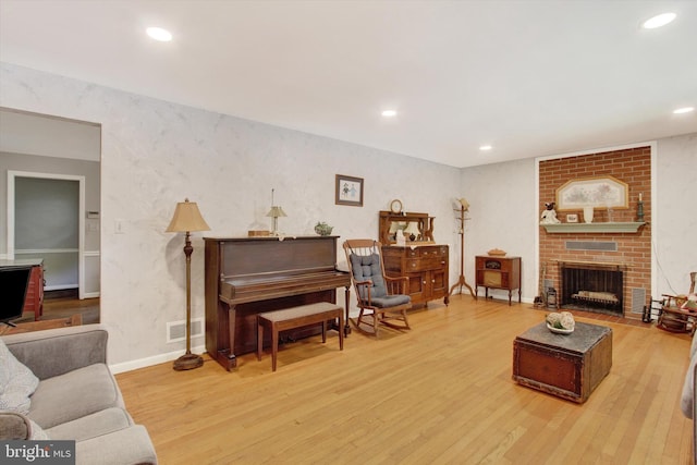 living area featuring wood finished floors, recessed lighting, a brick fireplace, and baseboards