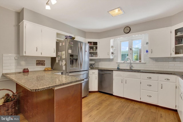 kitchen featuring appliances with stainless steel finishes, a sink, a peninsula, and decorative backsplash