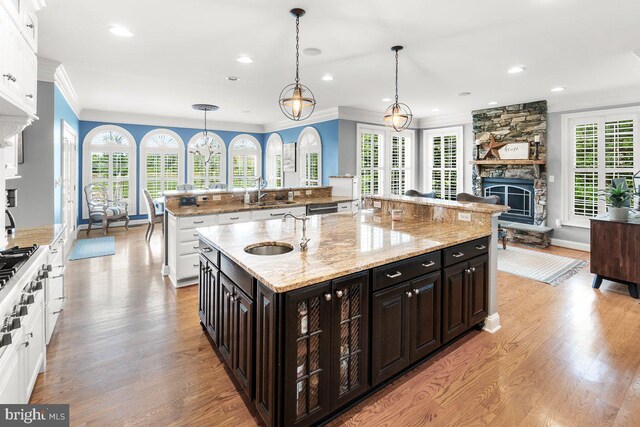 8170 Hollow Rd, Middletown, MD 21769 - kitchen featuring a stone fireplace, a sink, a large island, white cabinets, and ornamental molding