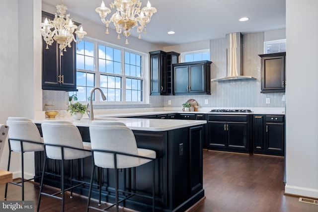 501 Triggerfish Dr, Oxon Hill, MD 20745 - kitchen with wall chimney exhaust hood, stainless steel gas stovetop, a kitchen bar, a chandelier, and backsplash