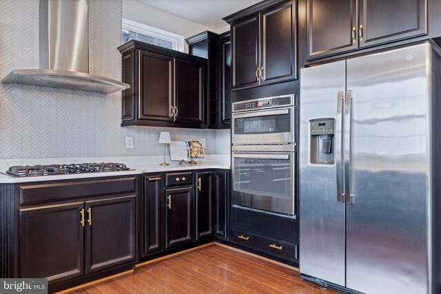 501 Triggerfish Dr, Oxon Hill, MD 20745 - kitchen with stainless steel appliances, wall chimney range hood, light countertops, wood finished floors, and backsplash