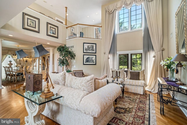 living area featuring healthy amount of natural light, a high ceiling, wood finished floors, and recessed lighting