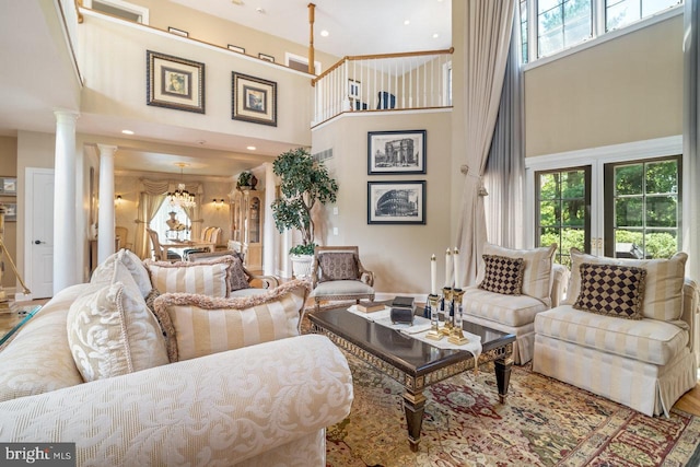 living area with a high ceiling, decorative columns, a chandelier, and recessed lighting