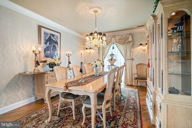 dining space with a chandelier, wood finished floors, crown molding, and baseboards