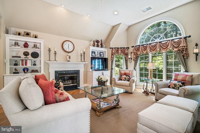 living room with a high end fireplace and vaulted ceiling
