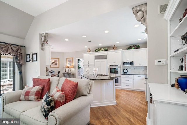 kitchen with appliances with stainless steel finishes, open floor plan, white cabinets, light wood-style flooring, and recessed lighting