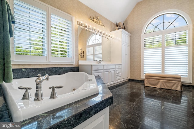 bathroom featuring vaulted ceiling, a jetted tub, vanity, granite tiled floors, and baseboards