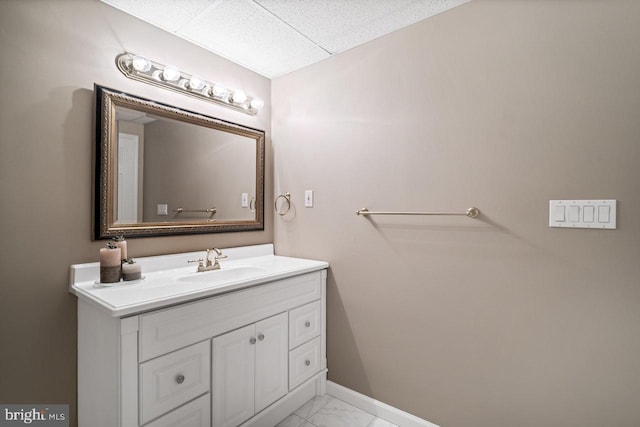 bathroom featuring marble finish flooring, a paneled ceiling, vanity, and baseboards