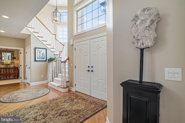 entryway featuring wood finished floors, stairs, baseboards, and recessed lighting