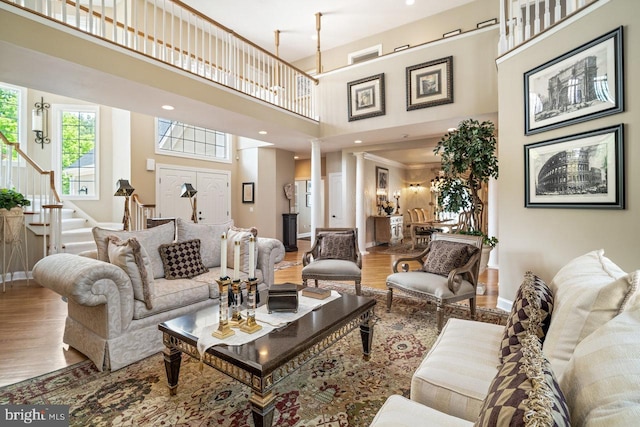 living area with wood finished floors, stairs, a high ceiling, and baseboards