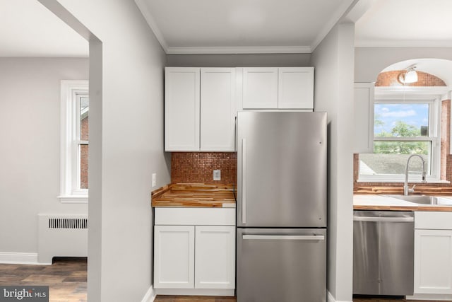2811 Westfield Ave, Baltimore, MD 21214 - kitchen featuring appliances with stainless steel finishes, radiator, white cabinets, decorative backsplash, and ornamental molding