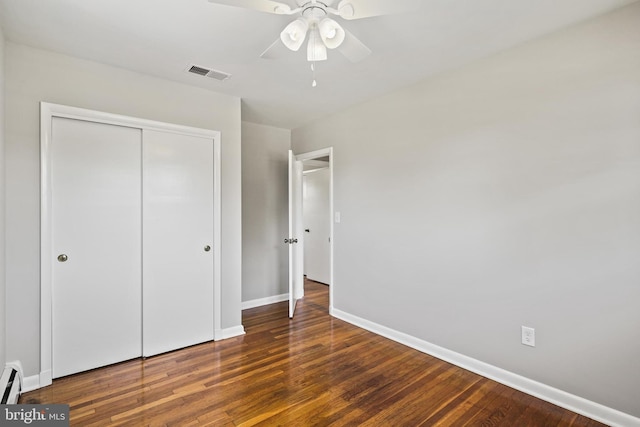 unfurnished bedroom with baseboards, a closet, wood finished floors, baseboard heating, and ceiling fan