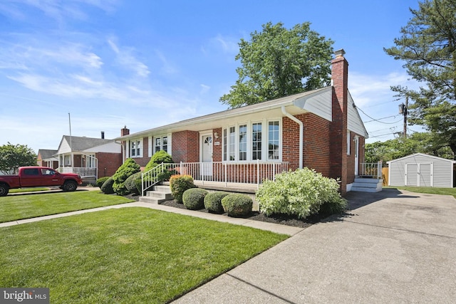 ranch-style house featuring a chimney, brick siding, a front lawn, driveway, and an outbuilding