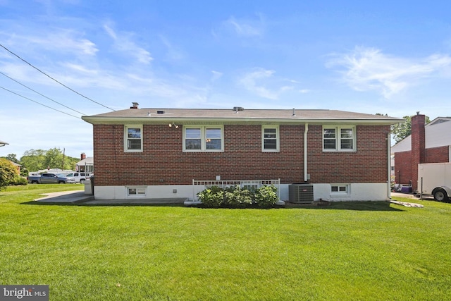 rear view of property featuring central AC unit, a yard, and brick siding