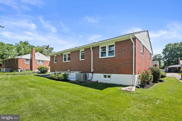 back of property featuring a yard, central AC, and brick siding