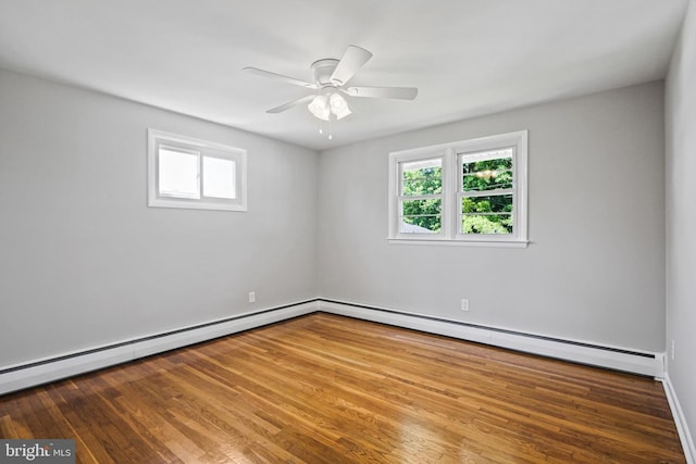 empty room with plenty of natural light, wood finished floors, and a baseboard radiator