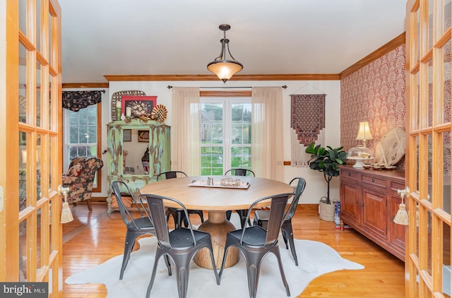 dining room featuring ornamental molding, light wood-type flooring, and baseboards