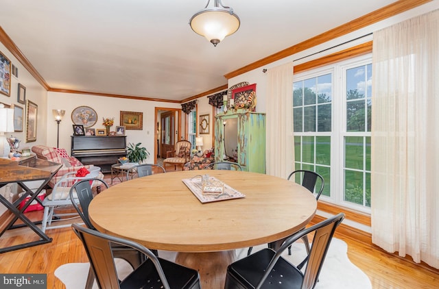 dining area featuring ornamental molding and light wood-style flooring