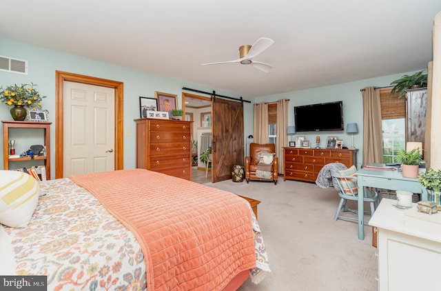 bedroom with a barn door, light colored carpet, and a ceiling fan