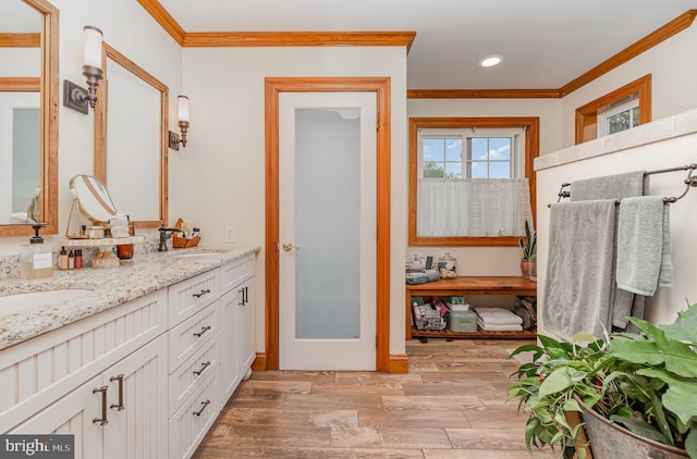 bathroom featuring ornamental molding, recessed lighting, double vanity, wood finished floors, and baseboards