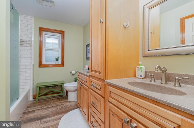 full bath with toilet, wood finished floors, and vanity