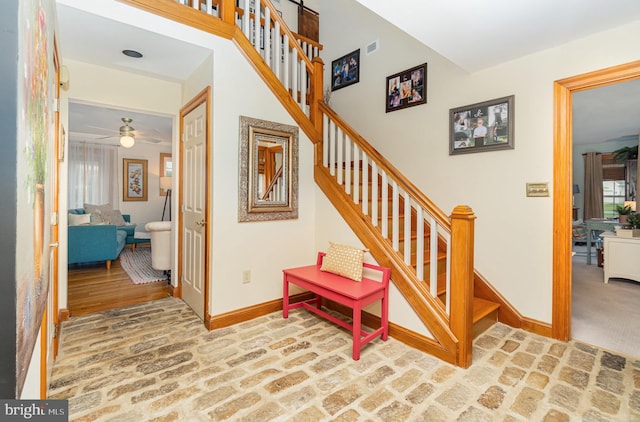 stairway with baseboards, brick floors, and a ceiling fan
