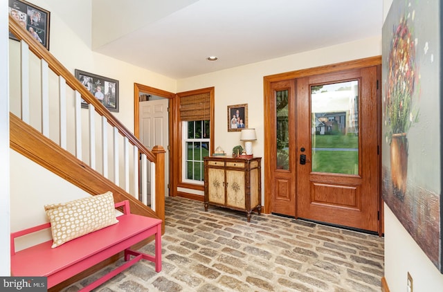 foyer featuring brick flooring, stairs, and recessed lighting