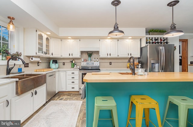 kitchen with appliances with stainless steel finishes, a breakfast bar area, decorative backsplash, and white cabinetry