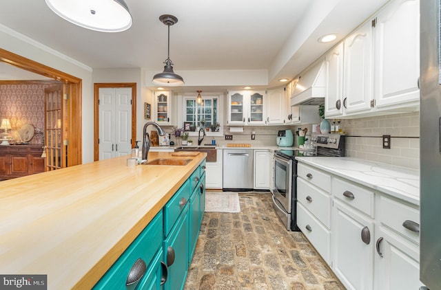kitchen with stainless steel appliances, custom exhaust hood, brick floors, white cabinetry, and a sink
