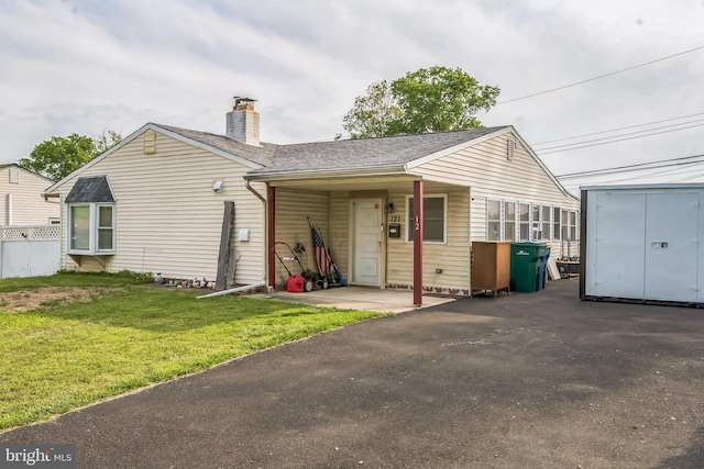 exterior space featuring a yard, a chimney, and a shingled roof