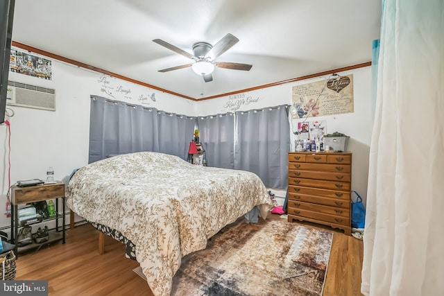 bedroom featuring wood finished floors, ornamental molding, a baseboard heating unit, ceiling fan, and a wall mounted AC