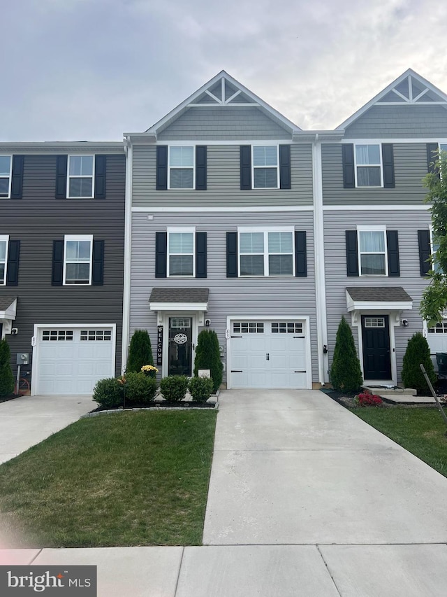 townhome / multi-family property featuring driveway, a garage, and a front yard