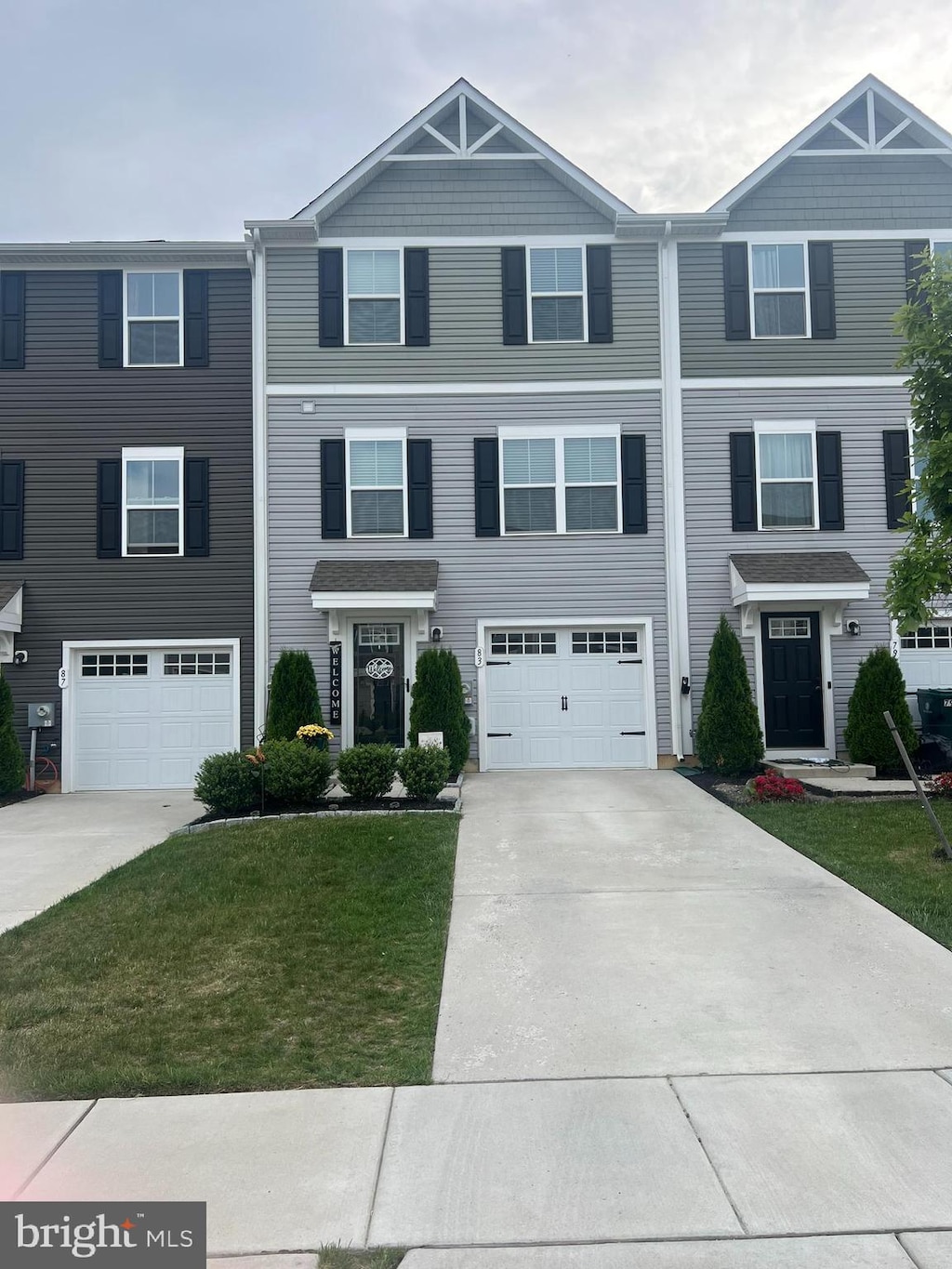 townhome / multi-family property featuring driveway, a garage, and a front lawn