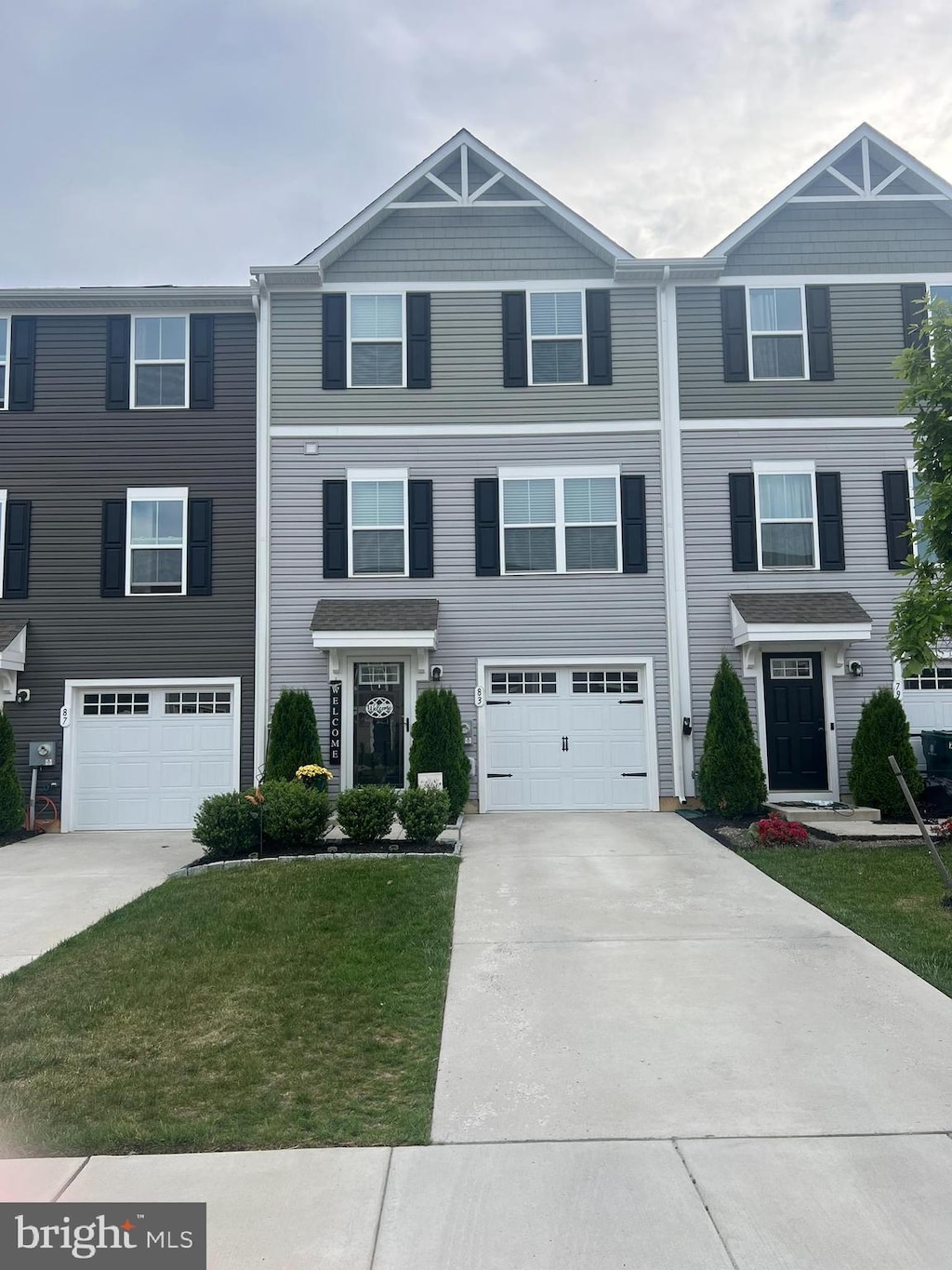 townhome / multi-family property featuring driveway, a garage, and a front lawn