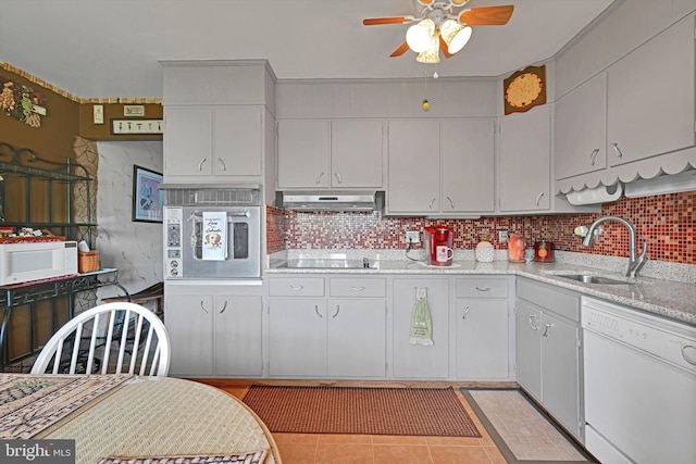 kitchen with white appliances, a sink, ceiling fan, under cabinet range hood, and tasteful backsplash