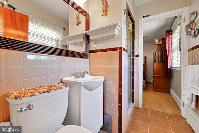 bathroom featuring tile walls, toilet, tile patterned flooring, vanity, and healthy amount of natural light