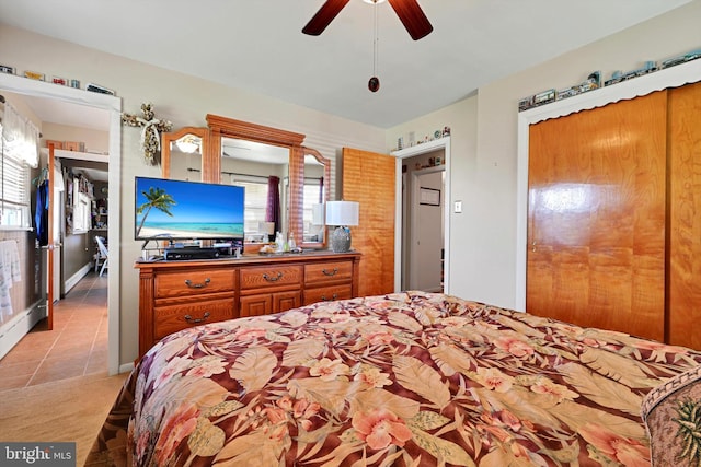 bedroom with light tile patterned flooring, light colored carpet, and ceiling fan