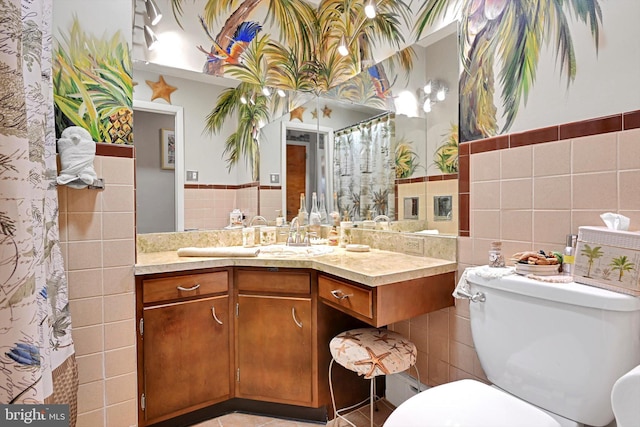 full bathroom featuring tile walls, wainscoting, toilet, and vanity