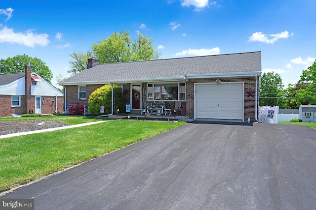 view of front facade featuring a garage, asphalt driveway, brick siding, a front yard, and covered porch