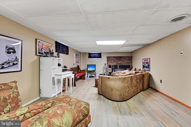 living room with a paneled ceiling, wood finished floors, a fireplace, and baseboards