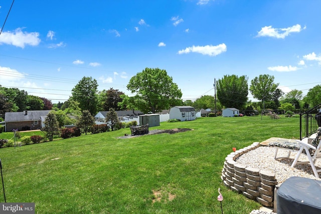 view of grassy yard featuring a storage shed, an outdoor structure, and a fire pit