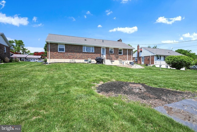 back of property with a lawn, a chimney, and brick siding