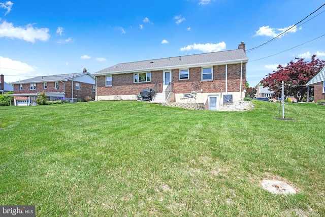 back of house featuring brick siding, a chimney, and a yard