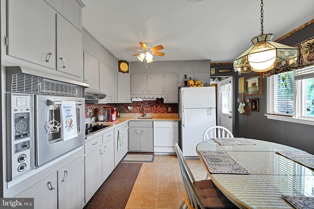 kitchen featuring white appliances, a sink, ceiling fan, light tile patterned flooring, and light countertops