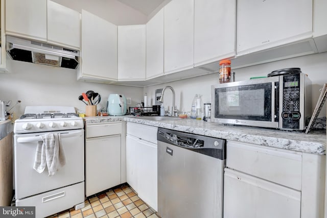 kitchen with appliances with stainless steel finishes, range hood, a sink, light countertops, and white cabinets